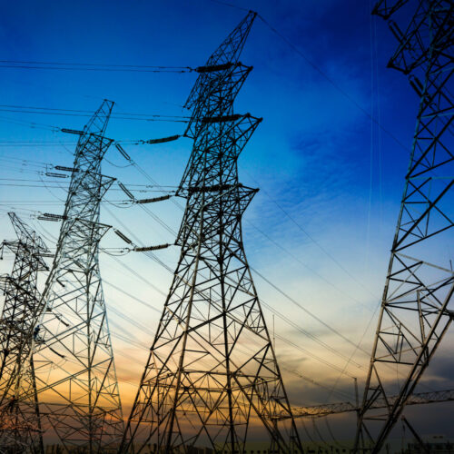 Sun setting behind the silhouette of electricity pylons