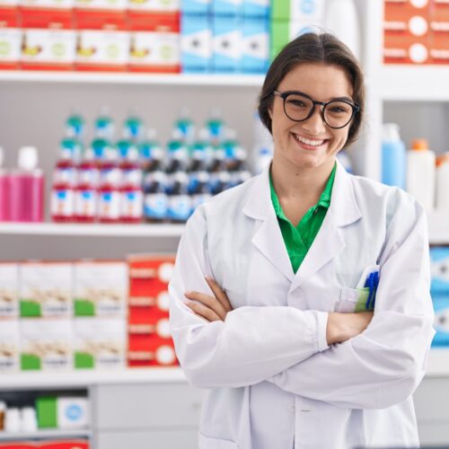 Young hispanic woman pharmacist smiling confident standing with arms crossed gesture at pharmacy